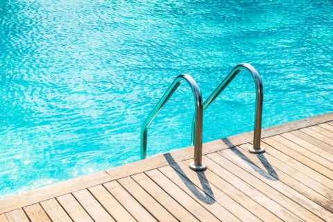 Piscine extérieure avec eau turquoise cristalline et échelle d'accès en inox à deux barreaux