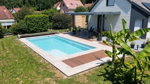 Jardin résidentiel avec piscine enterrée de forme libre, terrasse en dalles, pelouse entretenue