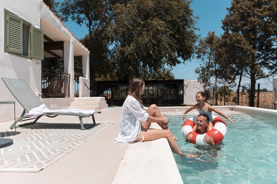Couple se détendant sur matelas pneumatiques gonflables dans piscine extérieure, eau turquoise cristalline